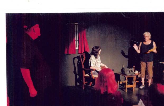 The ghost of Bert looks on as his widow, Sally, interacts with a visiting nurse.